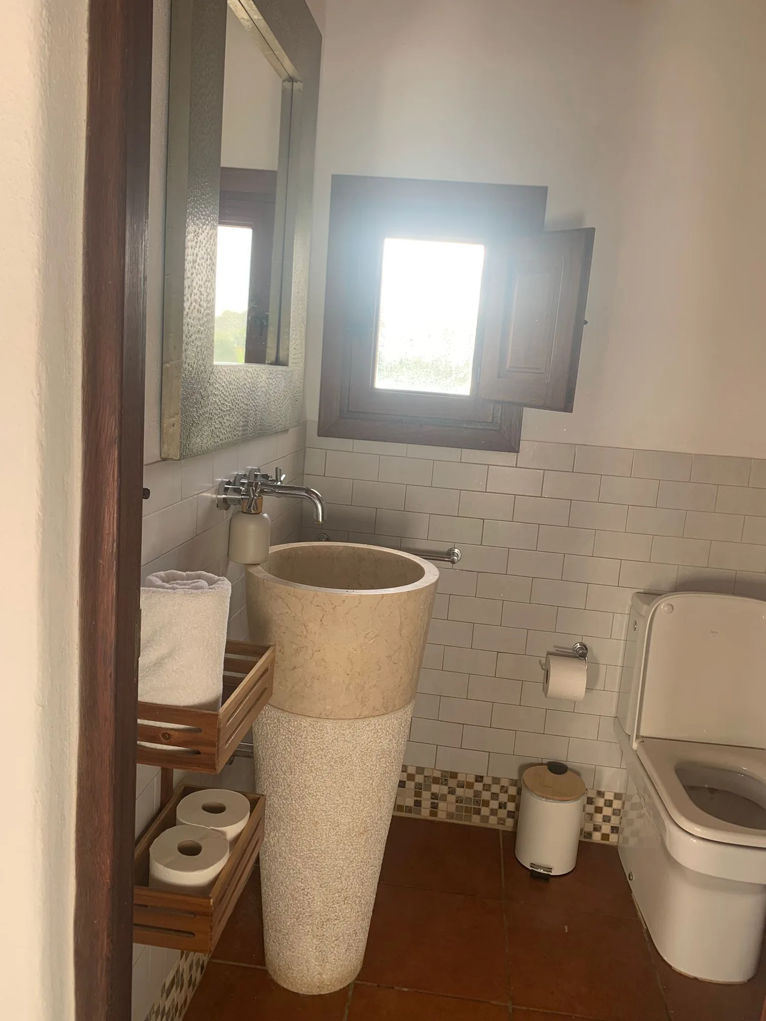Private bathroom with stone pedestal sink and natural daylight — La Casa de Mis Sueños
